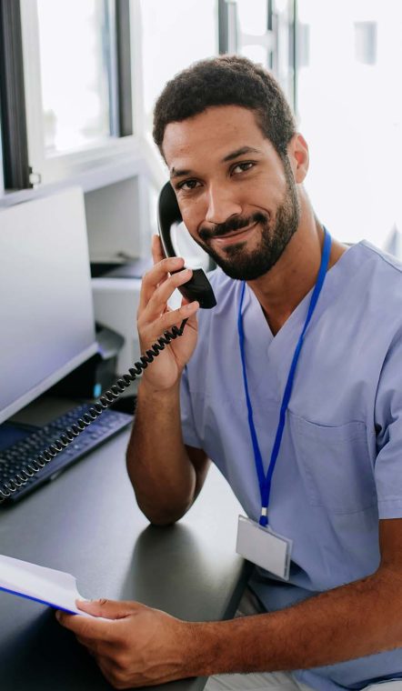 Portrait of young multiracial doctor sitting in his office and calling.